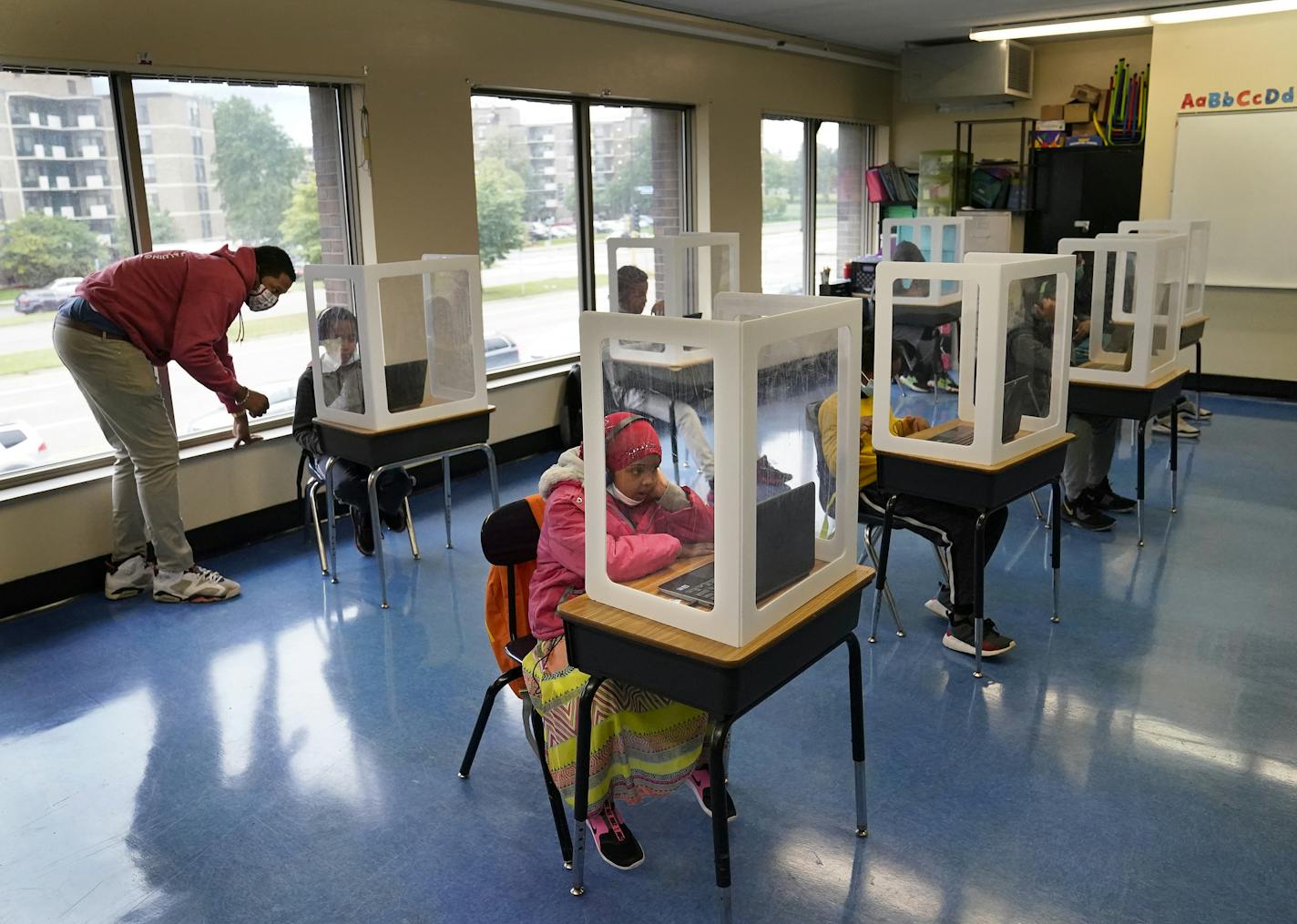 It was back to school for some students at Harvest Best Academy Tuesday in Minneapolis, but with masks, plastic barriers and other new precautions in the era of COVID-19. Here, para professional Jaevon Walton assisted a student in reconnecting to a zoom lesson in a learning pod of 2nd through 7th graders. ] DAVID JOLES • david.joles@startribune.com Tuesday, Sept. 8, 2020, in Minneapolis, MN Students in masks, distance learning, teachers talking to cameras in empty classrooms, lessons in tents an