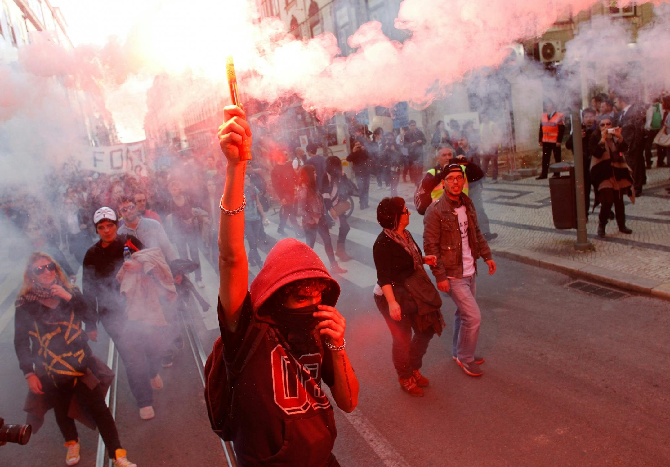 A protestors carries a lit flare while marching towards the Portuguese parliament in Lisbon during a general strike Monday, Nov. 14 2012. The second general strike in eight months in Portugal, where the government intends to intensify austerity measures next year, left commuters stranded as trains ground to a virtual halt and the Lisbon subway shut down.