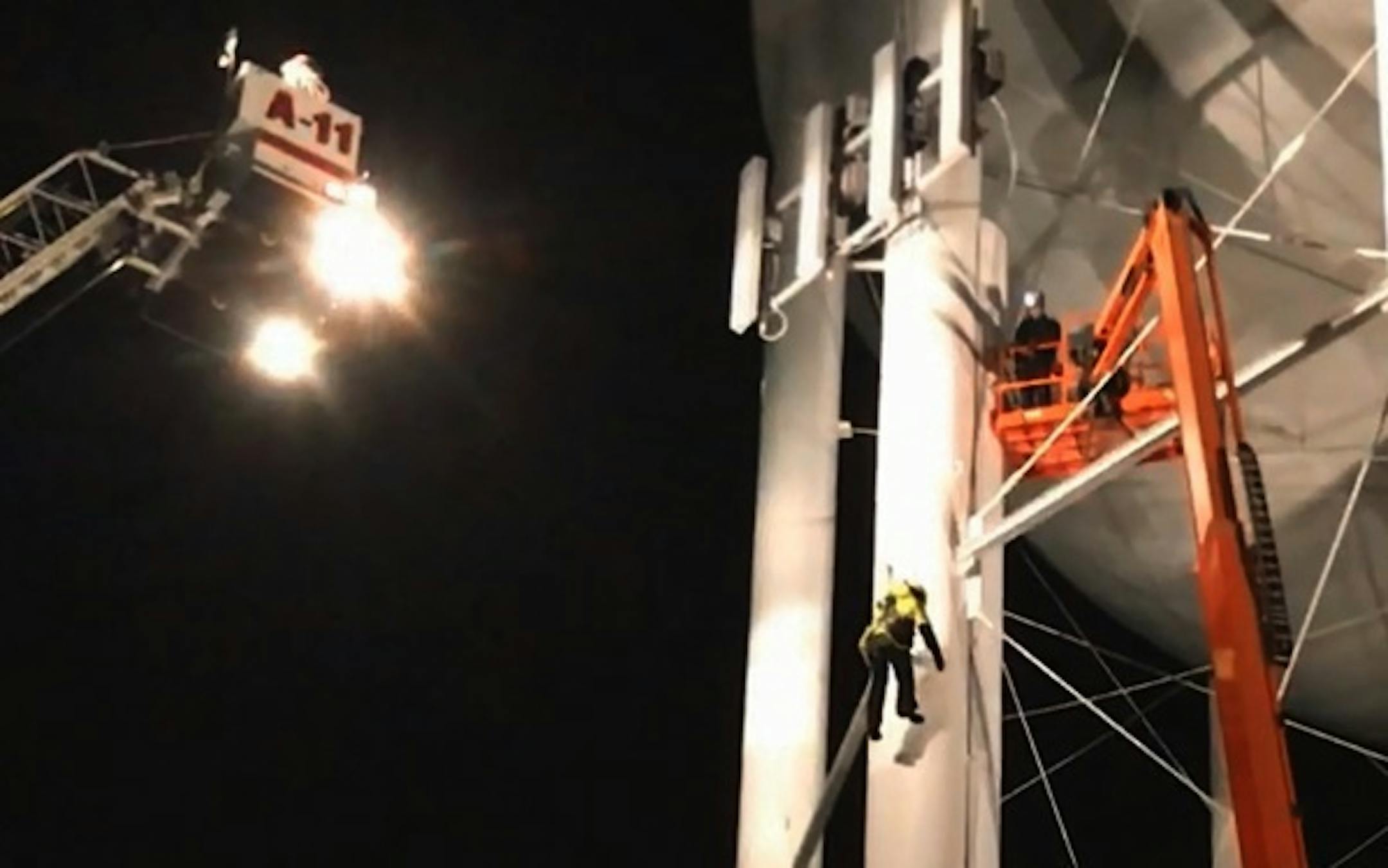 Rescue personnel bring down 1 of 3 workers from a water tower in Golden Valley, Mn.