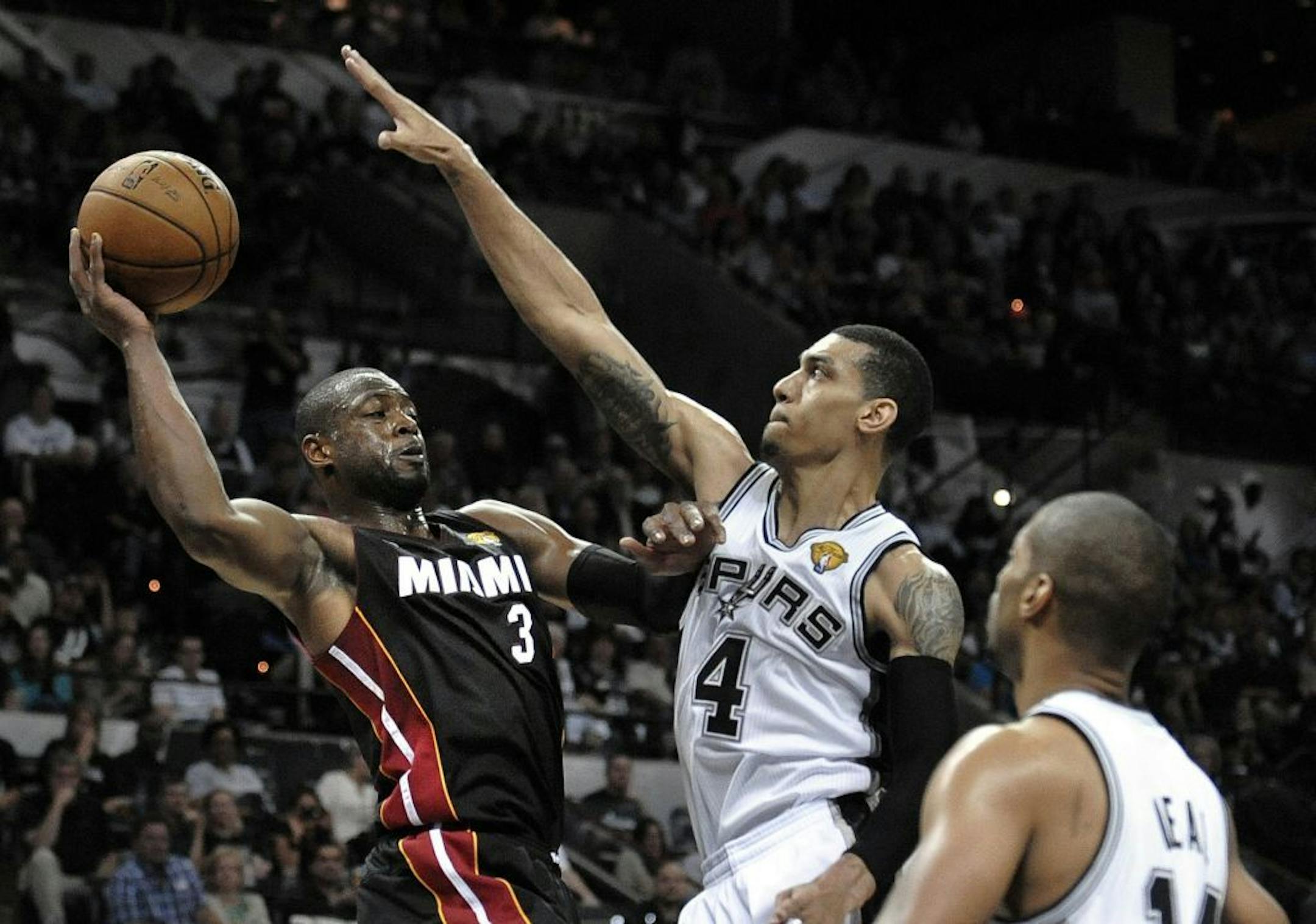 The Miami Heat's Dwyane Wade looks to pass the ball after driving on the San Antonio Spurs' Danny Green during the second quarter of Game 4 of the NBA Finals
