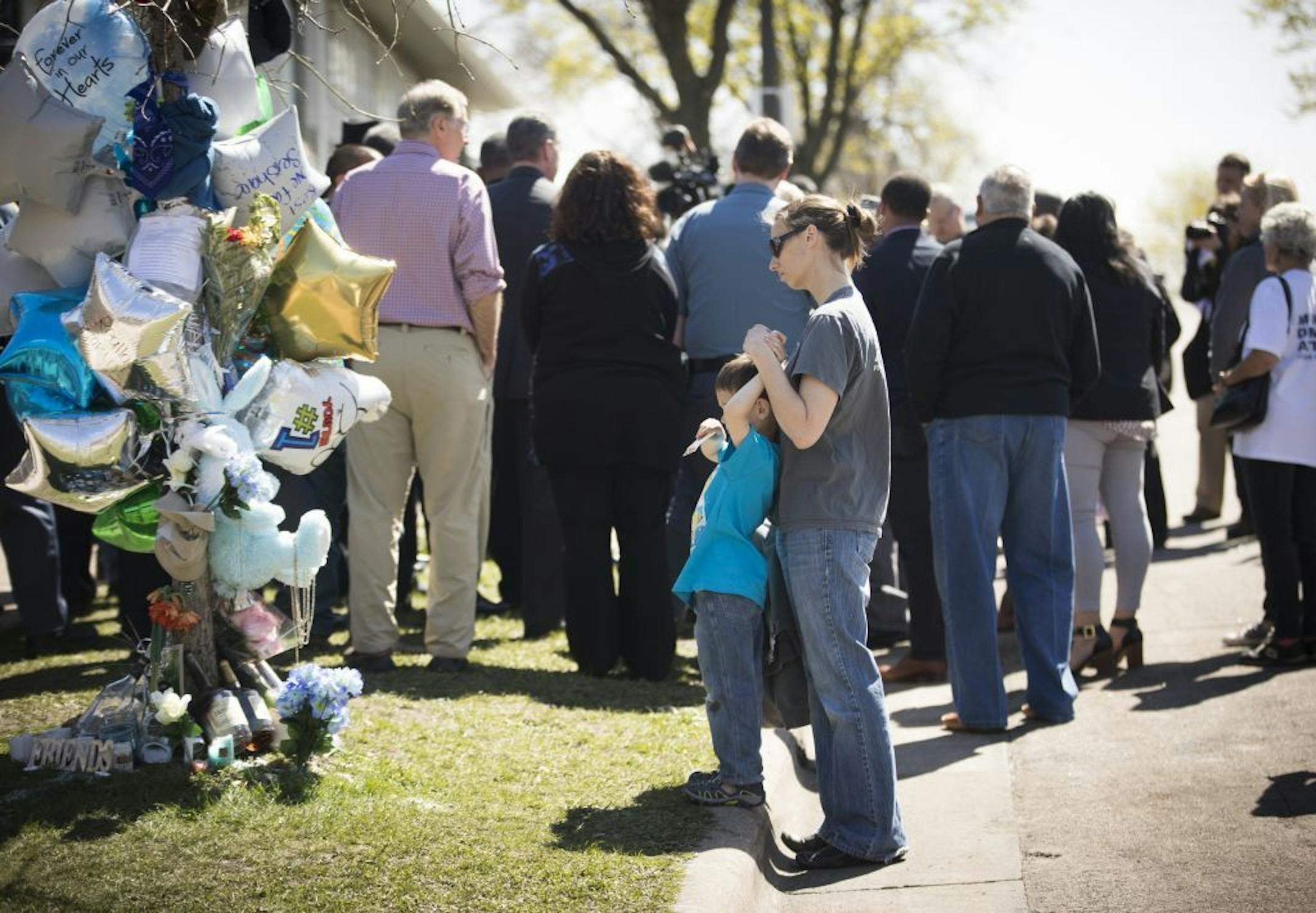 Annette Luther, of the Minnesota chapter of Moms demand Action, and her son Bennett Luther-Suhr stood looking at a memorial for Rondell Quantrell Dunn, who was shot a killed Monday, during a press conference by city officials in the spot to stand up against gun violence St. Paul, Minn., on Friday, April 21, 2017.