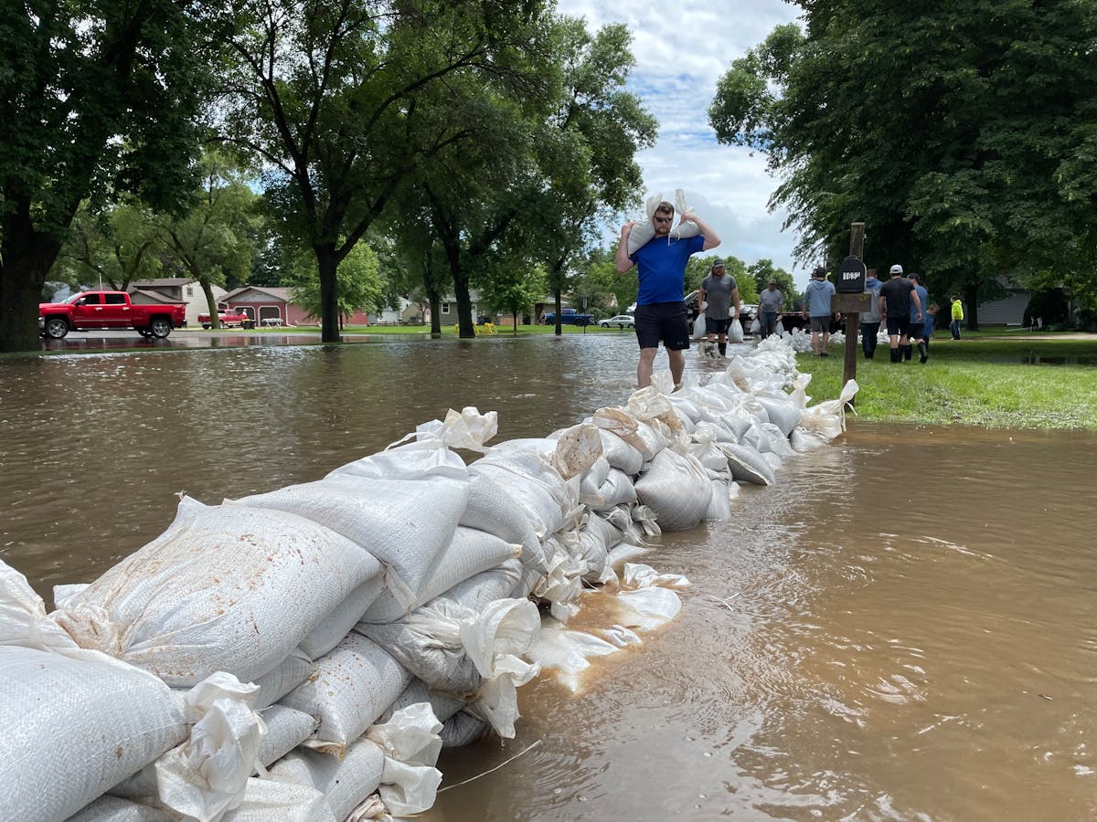 Randy Evers of Windom, Minn., stacks sandbags at the home of his friend Joe Fischenich, after flooding that swamped parts of the town June 22, 2024.
