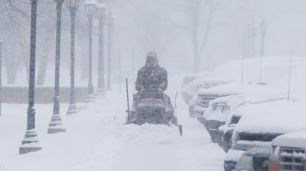 A man clears snow from the sidewalks around Friends University in Wichita, Kan.