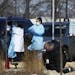 Medical staff wearing safety garments assist a driver at a new coronavirus drive-up test clinic, one of several in the metropolitan Twin Cities area, 