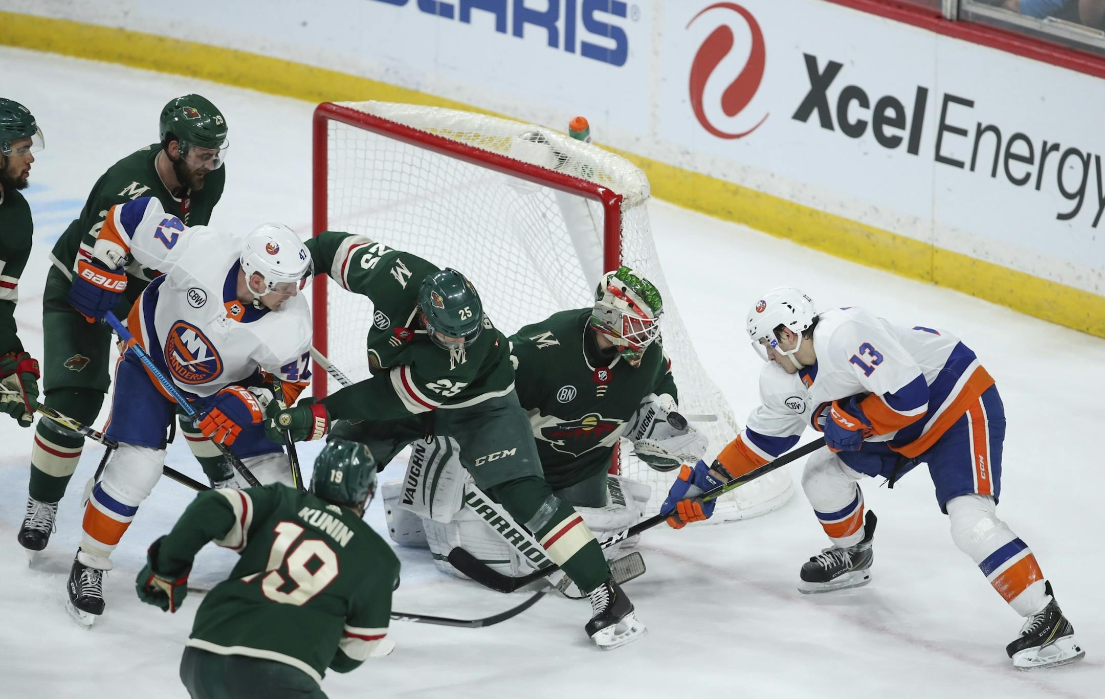Minnesota Wild goaltender Alex Stalock (32) gloved an airborne puck in front of New York Islanders center Mathew Barzal (13) in the third period while teammate Jonas Brodin (25) kept Islanders right wing Leo Komarov (47) at bay.