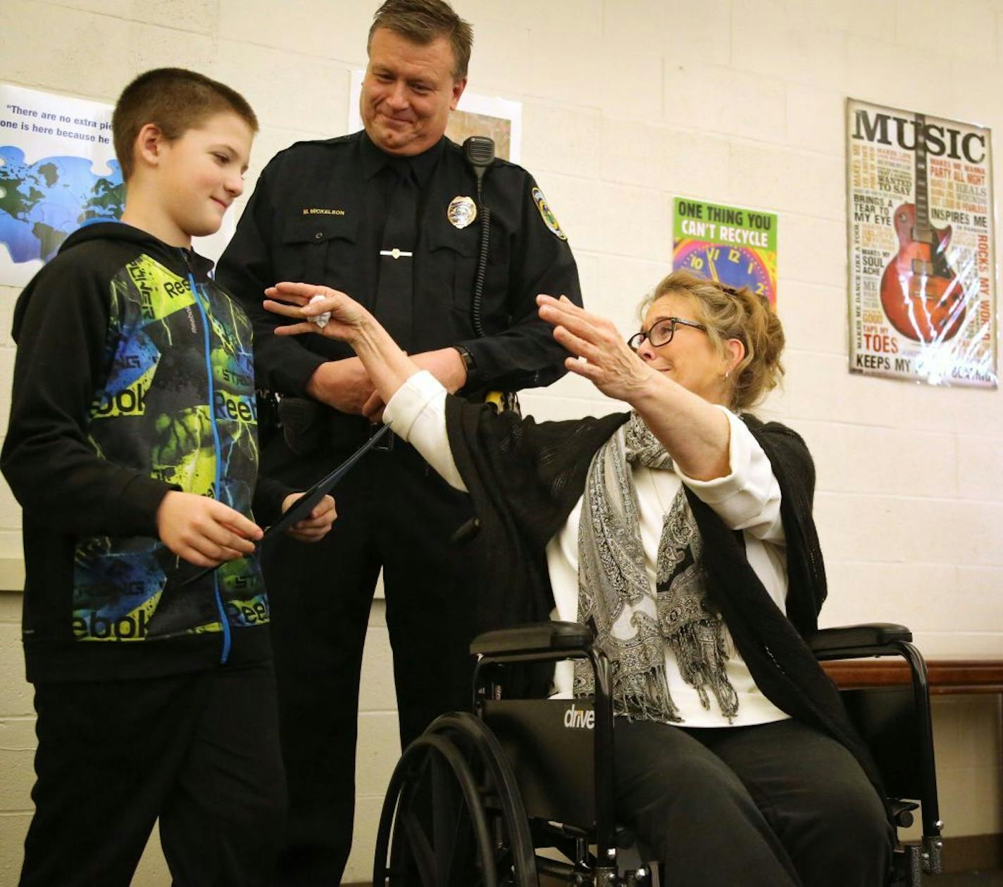 Fridley Middle School and Fridley Police Department recognized sixth grader Colby Hansen for his role in assisting injured homeowner Laurie Harms, who credits the boy with saving her life after she recently slipped and fell and shattered her hip and played for a few hours in the cold waiting for help before Hansen came to the rescue and called 911 and got medical assistance for Harms. Here, as Fridley Police SRO Mark Mickelson looks on Hansen, left, leans in for a hug from Harms Tuesday, Feb. 14