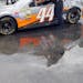 Crew members for Scott Riggs push his car through puddles between stations during tech inspection for the NASCAR Sprint Cup auto race at Kentucky Spee