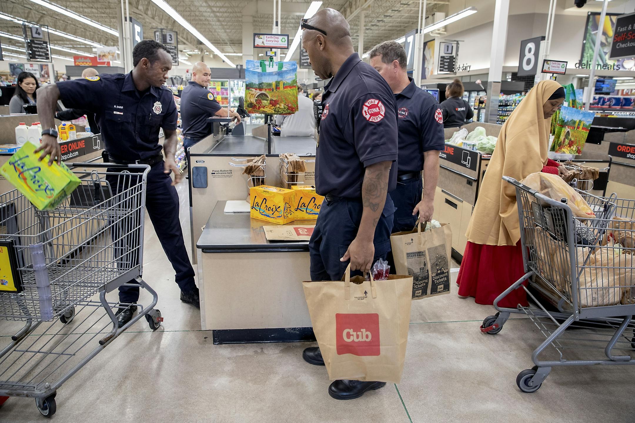 St. Paul firefighter Mohamed Daoud, left, along with Station 23 firefighters, Captain Tomo Klepp, left, Will Smith, center, and Derek Frans, right, made a trip to the grocery store during his second day on the job as one of the first Somali Americans to be sworn into the St. Paul fire department.
