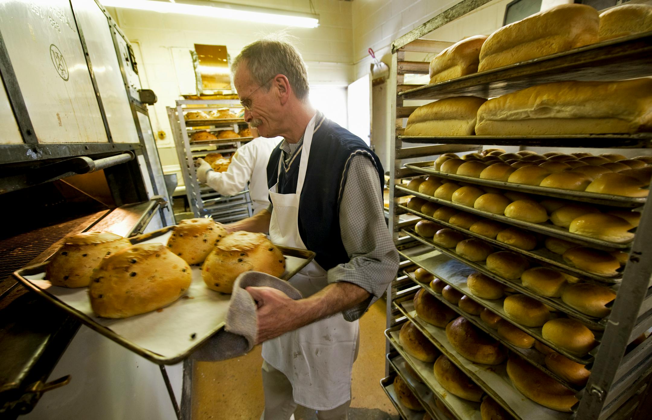 Scandia Bakery owner Gary Arvidson, along with head baker Tom Aarsvold, rear, removed julekaka from the oven to cooling racks on Monday. Arvidson's landlord refused to extend the lease on the bakery, saying Arvidson often has been late with the rent. Arvidson says he doesn't have the $20,000 to move the shop.
