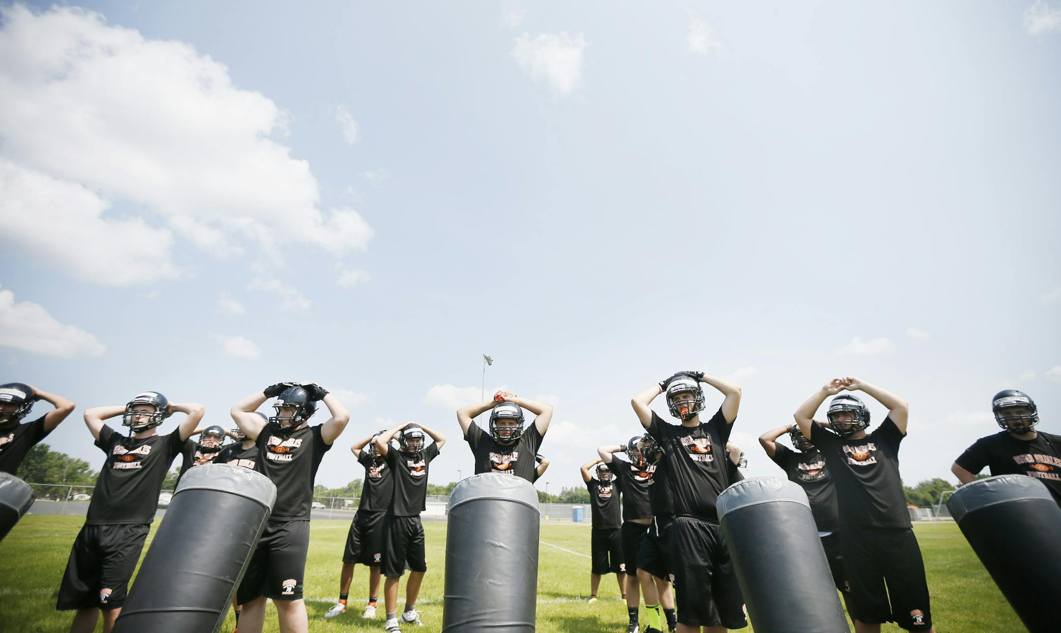Members of the Osseo fotball team’s offensive line took a breather from sled drills under a blue sky Monday.