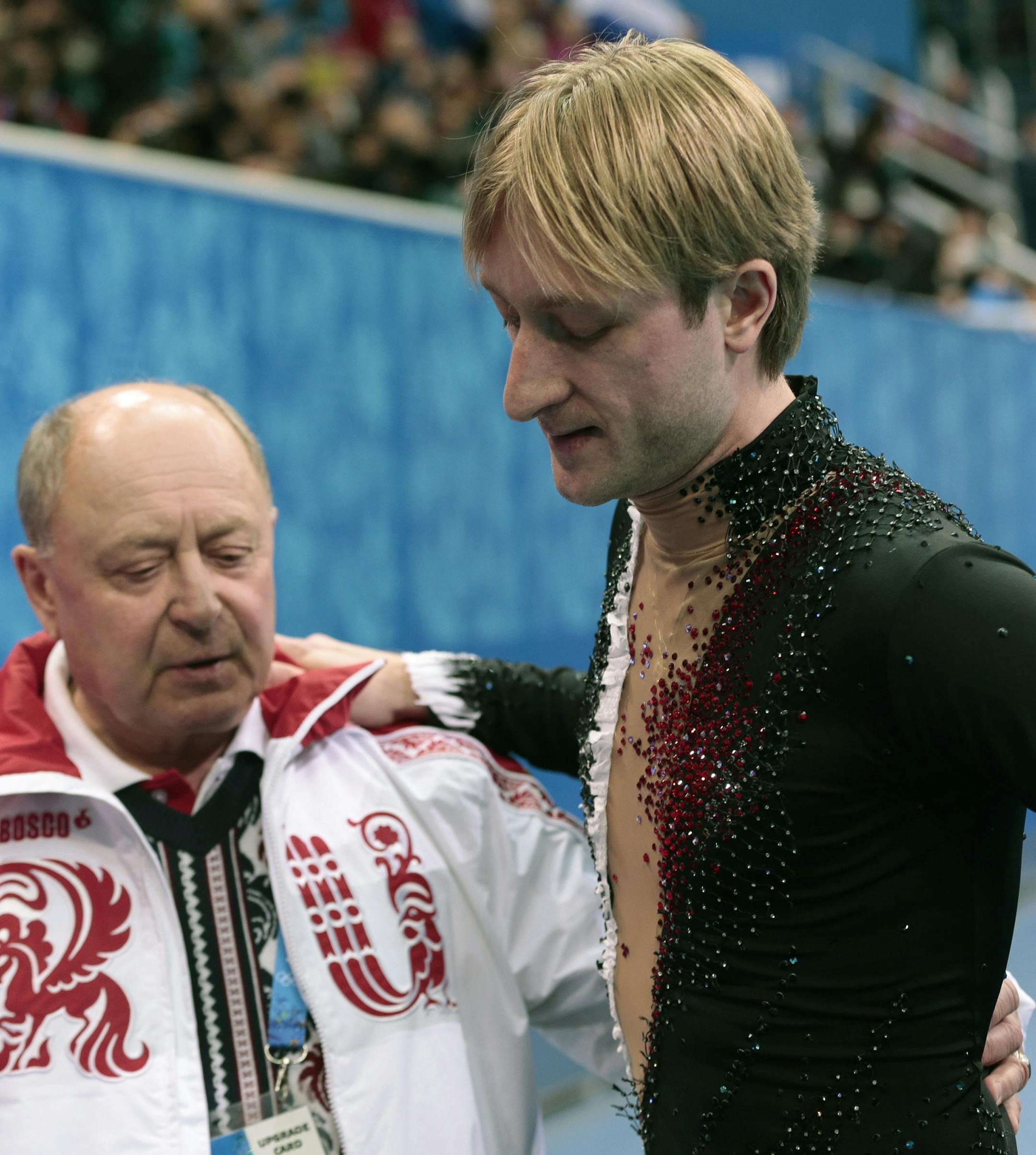 Evgeni Plushenko of Russia, right, and his coach Alexei Mishin leave after Plushenko pulled out of the men's short program figure skating competition due to illness at the Iceberg Skating Palace during the 2014 Winter Olympics, Thursday, Feb. 13, 2014, in Sochi, Russia. (AP Photo/Ivan Sekretarev)