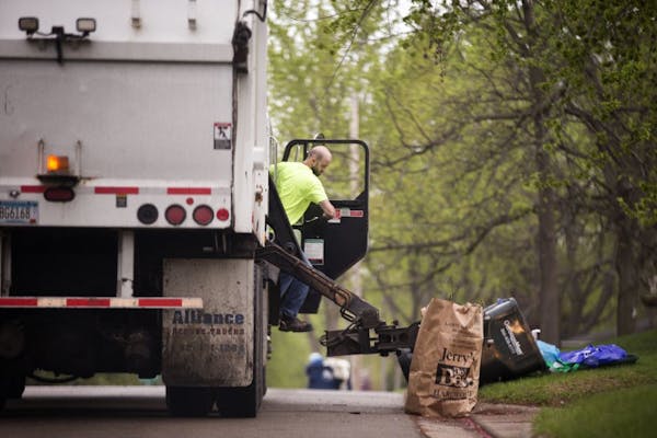 A GarbageMan worker empties containers onto the truck on trash pickup day in Bloomington between France Avenue and Normandale Boulevard on Thursday, M