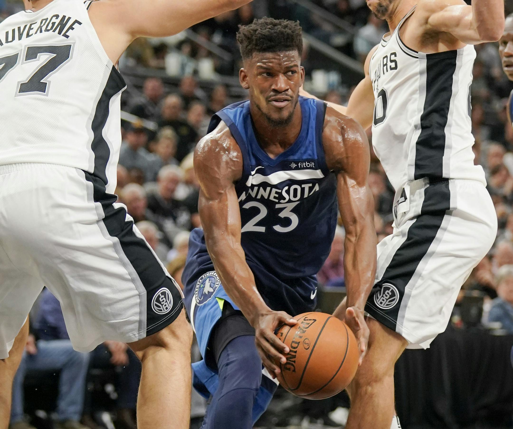 Minnesota Timberwolves' Jimmy Butler (23) looks to pass as he drives between San Antonio Spurs' Joffrey Lauvergne, left, of France, and Manu Ginobili, of Argentina, during the first half of an NBA basketball game, Wednesday, Oct. 18, 2017, in San Antonio. (AP Photo/Darren Abate) ORG XMIT: TXDA101