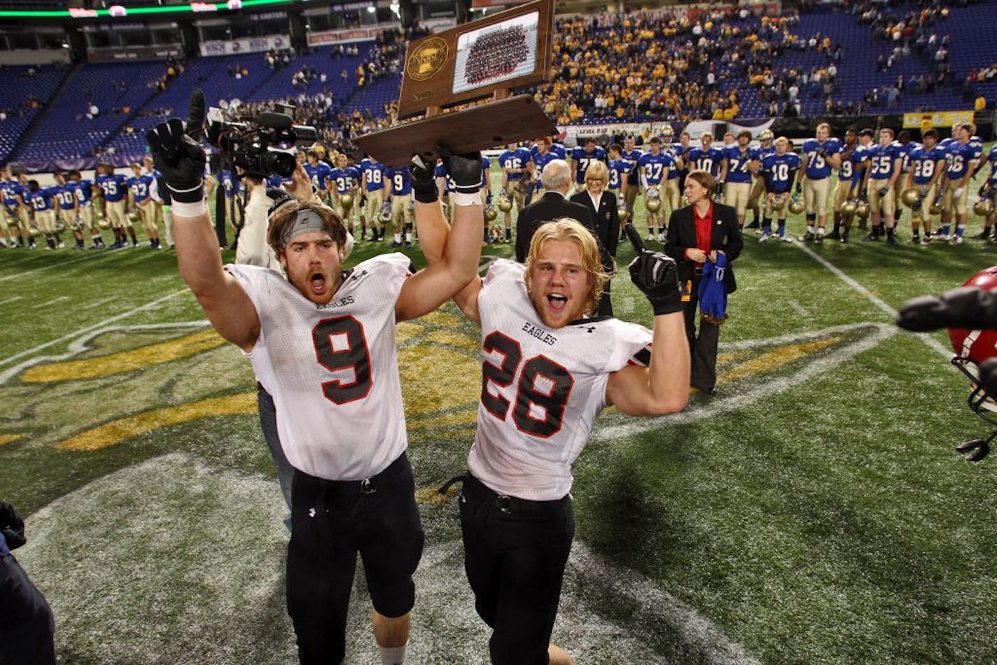 Eden Prairie captains Drake Michaelson (9) and Andrew Larson (28) celebrated with the 5A trophy after defeating Wayzata 13-3 in the Prep Bowl.