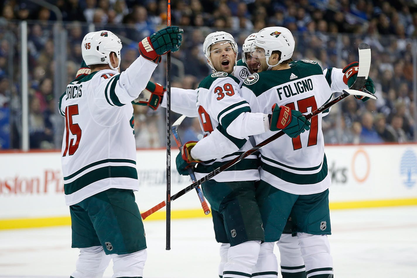 The Wild's Matt Hendricks (15), Nate Prosser (39), Matt Bartkowski (44) and Marcus Foligno (17) celebrate Bartkowski's goal against the Jets during first period