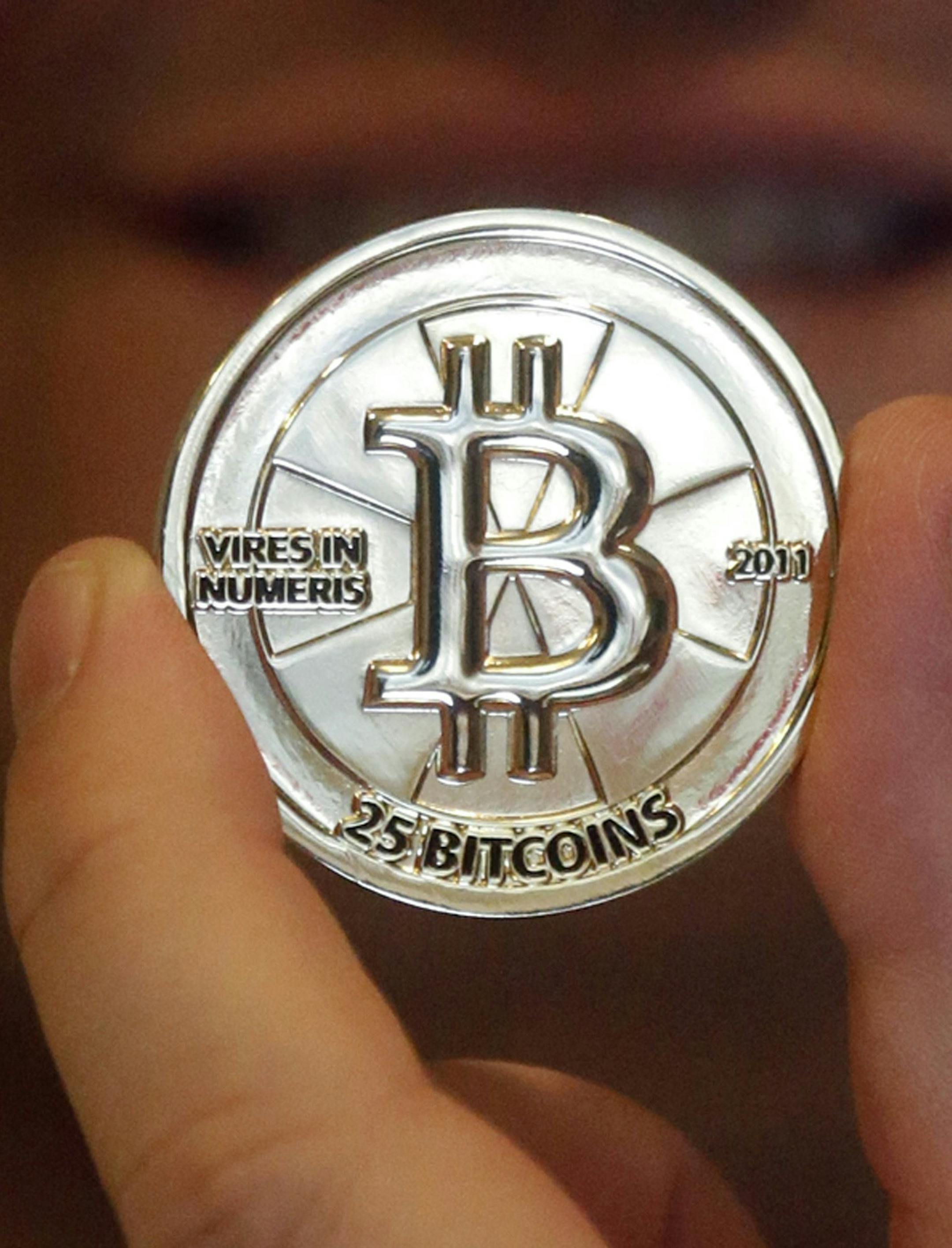 FILE - In this April 3, 2013 file photo, Mike Caldwell, a 35-year-old software engineer, holds a 25 Bitcoin token at his shop in Sandy, Utah. As Venezuelaís national currency loses value at a catastrophic rate, thousands have begun turning to the world of cryptocurrency to salvage what little value remains from their increasingly worthless bolivars. (AP Photo/Rick Bowmer, File) ORG XMIT: XFLL302