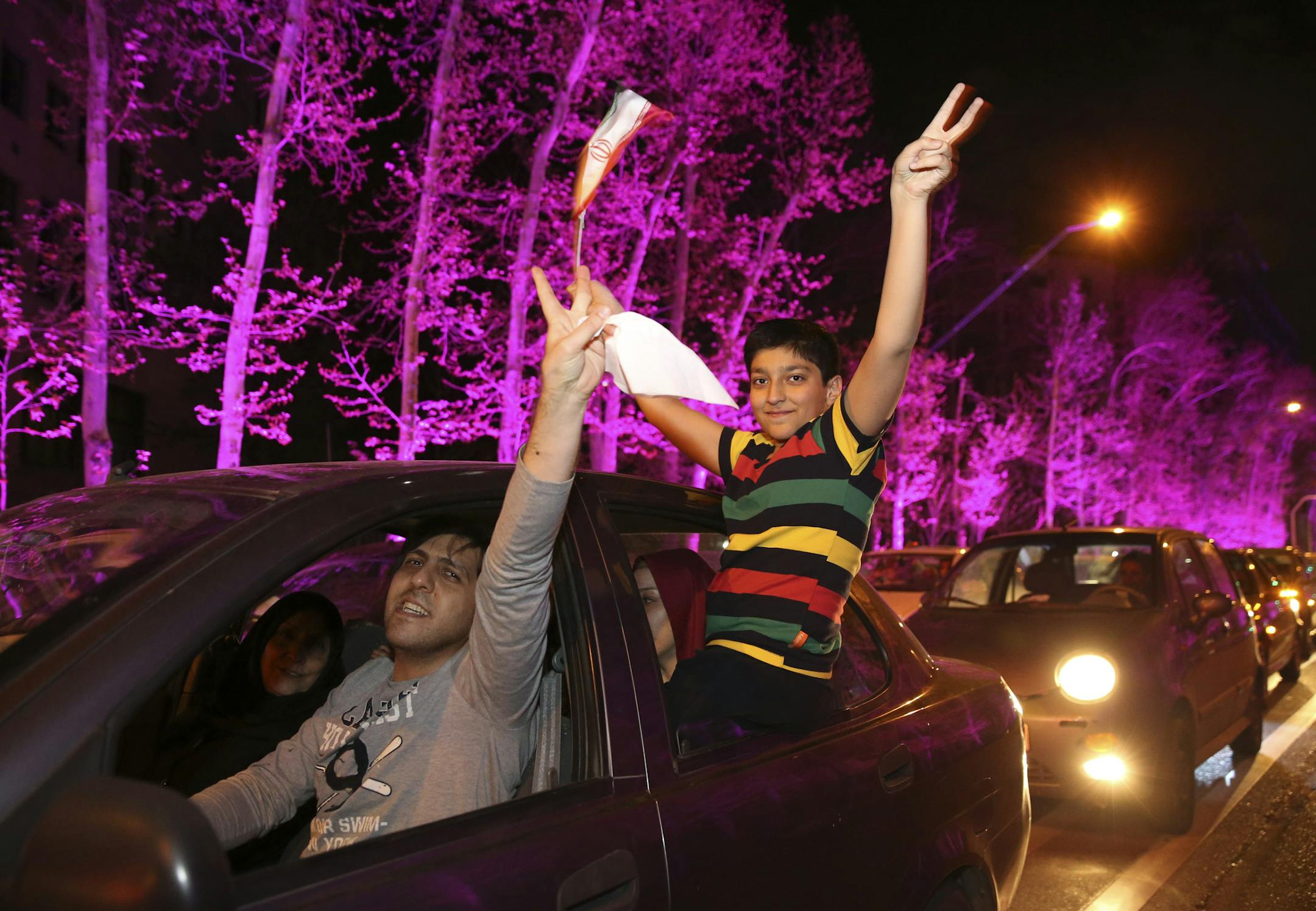 Iranians flash the victory sign as one of them waves a representation of the country's national flag from their car while celebrating on a street in northern Tehran, Iran, Thursday, April 2, 2015, after Iran's nuclear agreement with world powers in Lausanne, Switzerland. Iran and six world powers reached a preliminary nuclear agreement Thursday outlining commitments by both sides as they work for a comprehensive deal aiming at curbing nuclear activities Tehran could use to make weapons and provi
