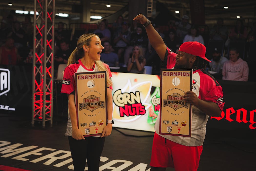 Model Paige Hathaway celebrates with cornhole pro AJ Sims after the two won a prelim for the ACL SuperHole Series in Fort Worth, Tx.