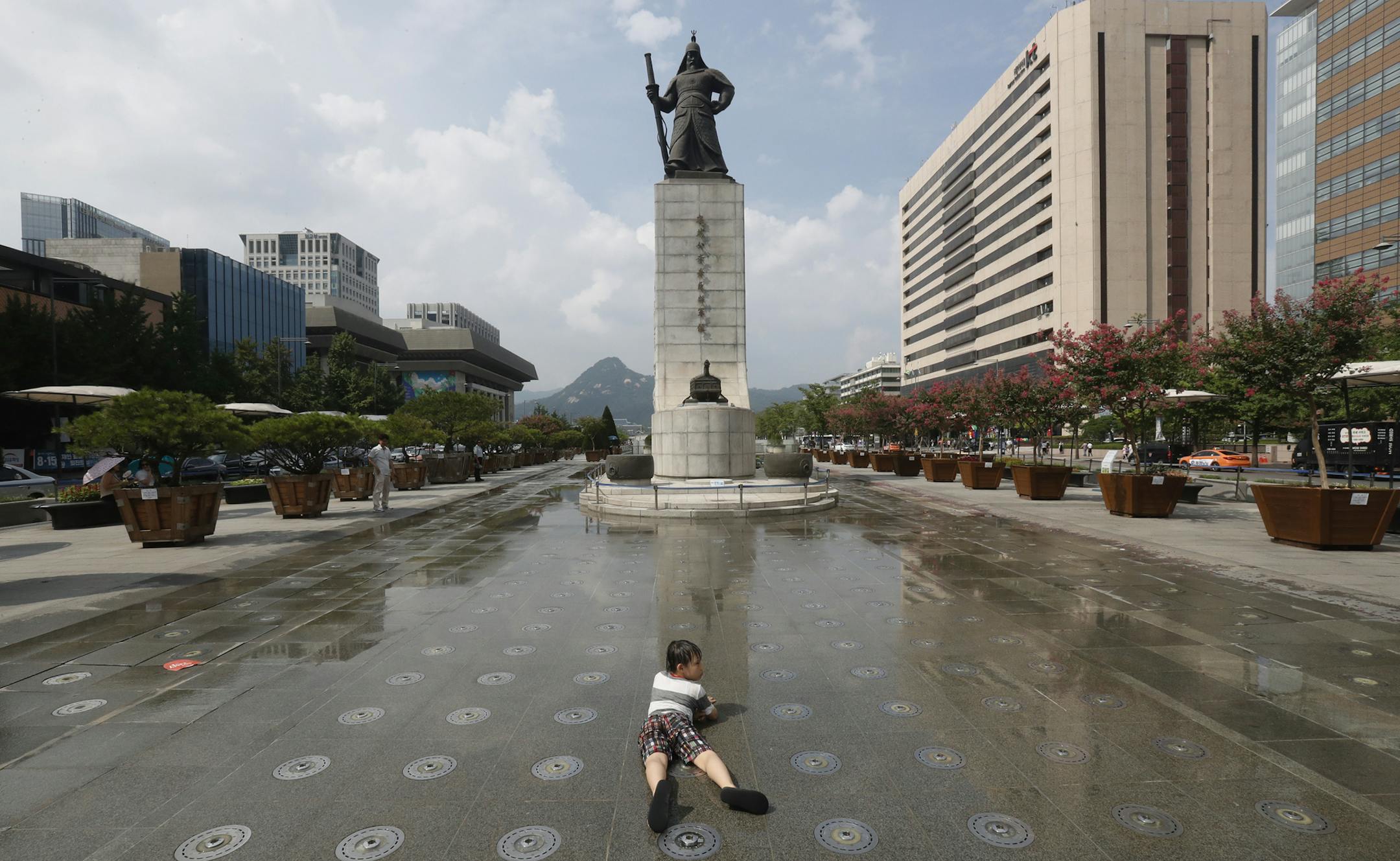 A boy lies down as he waits for the fountain to sprinkle water in Seoul, South Korea, Thursday, Aug. 8, 2019. A heat wave warning was issued in Seoul as temperatures soared above 32 degrees Celsius (90 degrees Fahrenheit). (AP Photo/Ahn Young-joon) ORG XMIT: SEL109