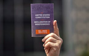 A person holds a copy of the Constitution of the United States of America and Declaration of Independence at a May Day rally for the Rule of Law, May