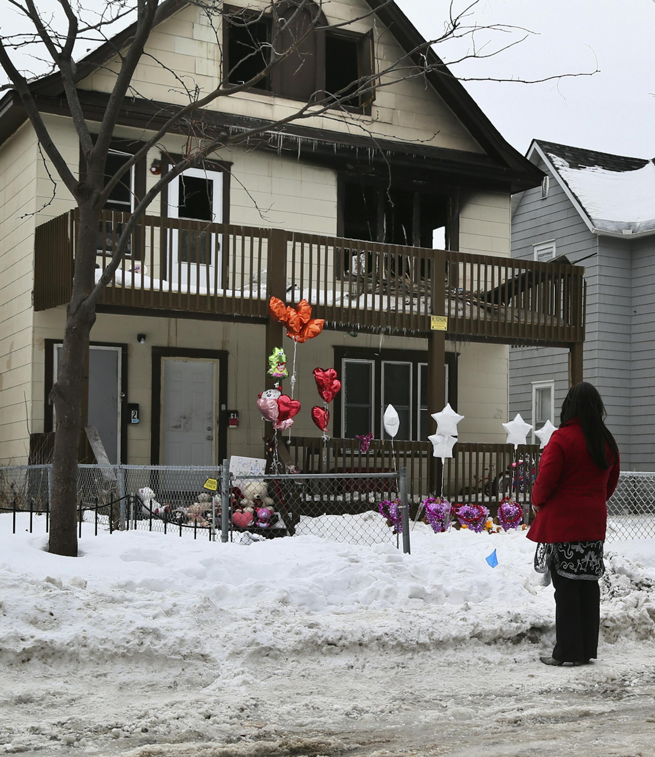 Northside resident Loritha Clark pauses in the street while taking in the scene of the fatal fire Saturday, Feb. 15, 2014, in Minneapolis, MN. Clark described it as "so sad," adding that some of her northside neighbors can't afford to buy smoke alarms to alert themselves to a fire.](DAVID JOLES/STARTRIBUNE) djoles@startribune.com A day after a northside fire took the lives of five, including three children, a steady stream of vehicles with onlookers inside rolled slowly by the duplex, some snapp
