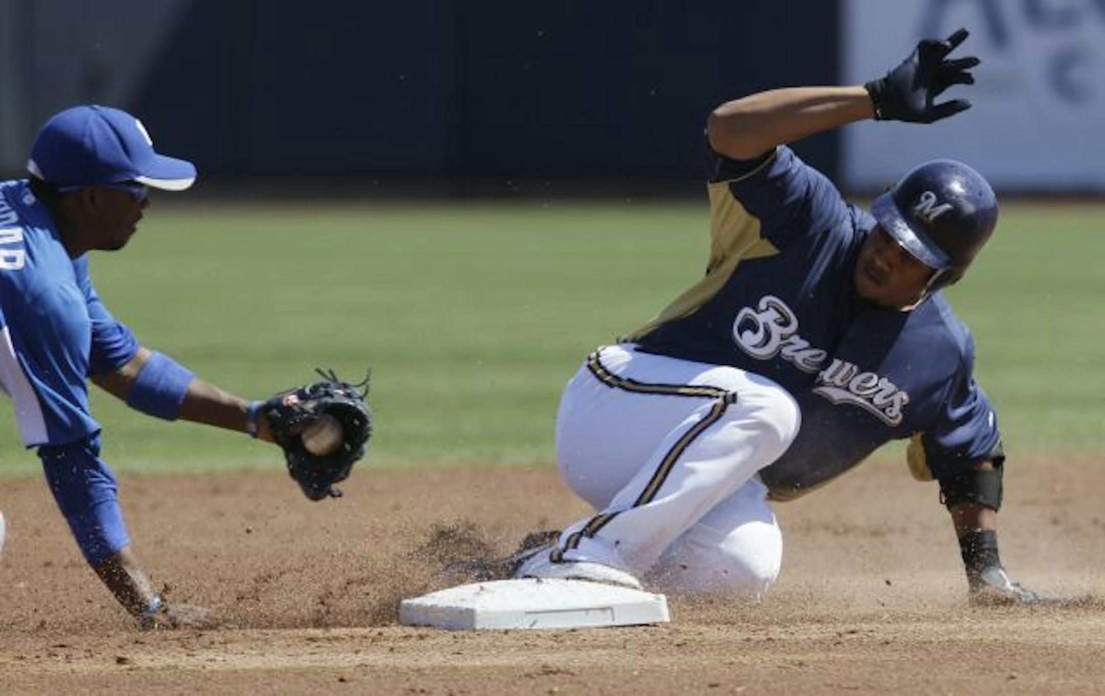 Milwaukee Brewers' Carlos Gomez, right, is safe at second base after hitting a double as Kansas City Royals shortstop Alcides Escobar applies a late tag during the first inning of a spring training baseball game on Sunday, March 13, 2011, in Phoenix.