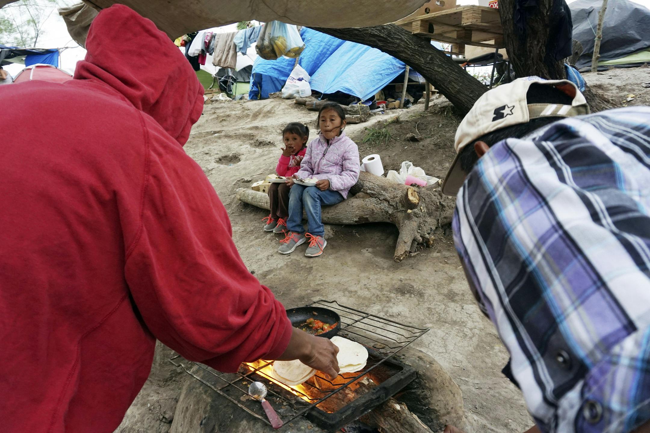 A migrant family prepares a hot meal at a makeshift migrant camp in Matamoros, Mexico, Tuesday, Dec. 10, 2019. (Miguel Roberts/The Brownsville Herald via AP) ORG XMIT: MERa7475a98c44a0a72aeb81b9e67d76