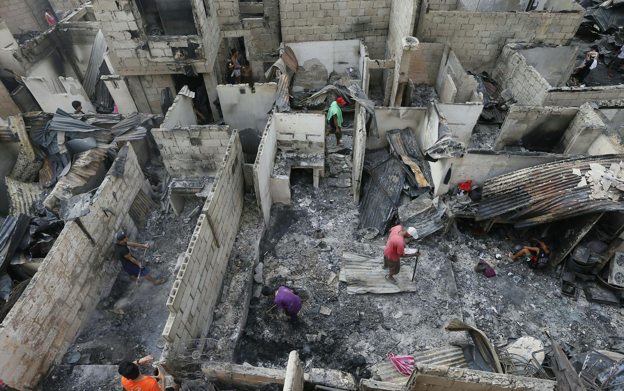 Fire survivors sift through the debris, a day after a huge fire razed an informal settlers' community in suburban Mandaluyong city, east of Manila, Philippines Thursday, Nov. 26, 2015. Fire officials say no casualties were reported but around 800 houses were razed and thousands of informal settlers were rendered homeless. (AP Photo/Bullit Marquez)