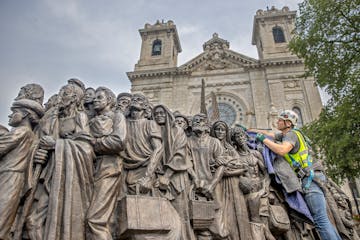 Craig Schulz unveils a statue called “Angels Unaware,” which was placed near the steps of the Basilica of St. Mary on Friday.