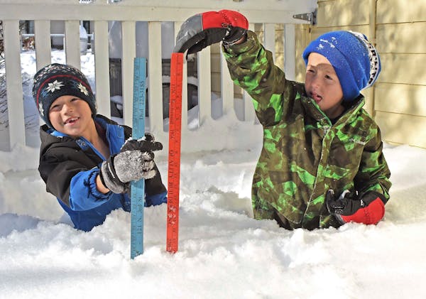 Two boys measured the snow depths near their home in north Bismarck, N.D., on Friday, Nov. 11, 2022. 
