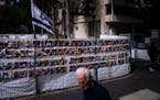 People pass by a fence with photographs of Israelis who are being held hostage in the Gaza Strip by the Hamas militant group, in Ramat Gan, Israel, Th