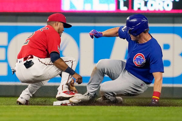 Chicago Cubs' Patrick Wisdom, right, beats the tag by Twins second baseman Luis Arraez in the seventh inning