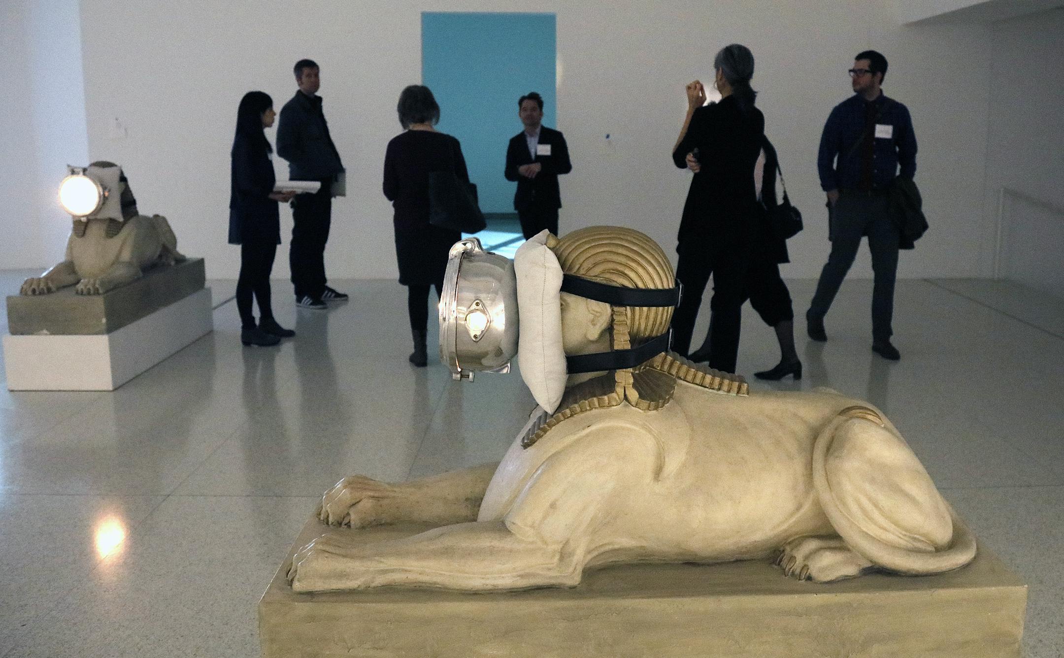 A pair of updated sphinxes by Trisha Donnelly illuminate a gallery of Walker visitors and staff.