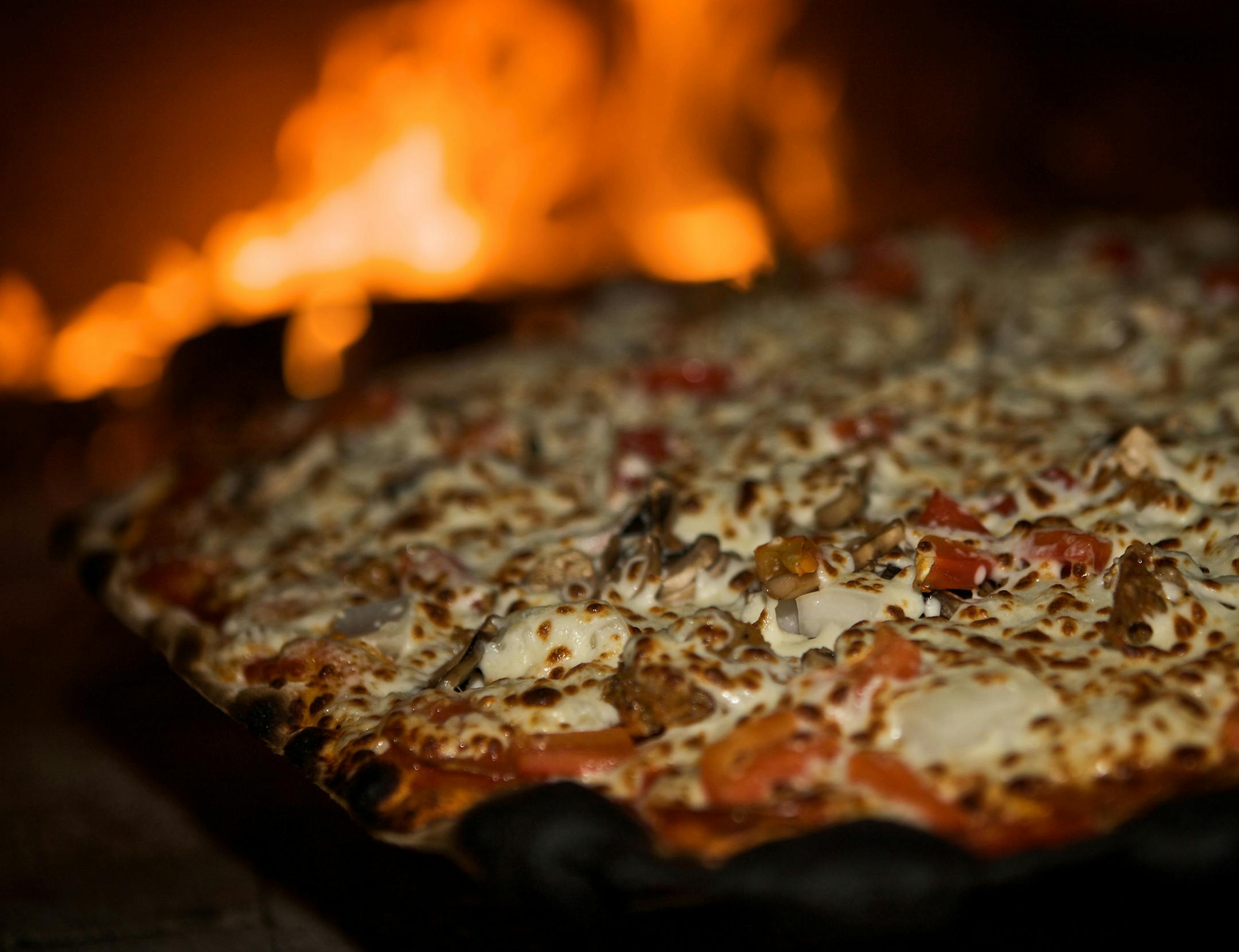 A pizza spends its final seconds inside the wood-burning oven at the Stone Barn.