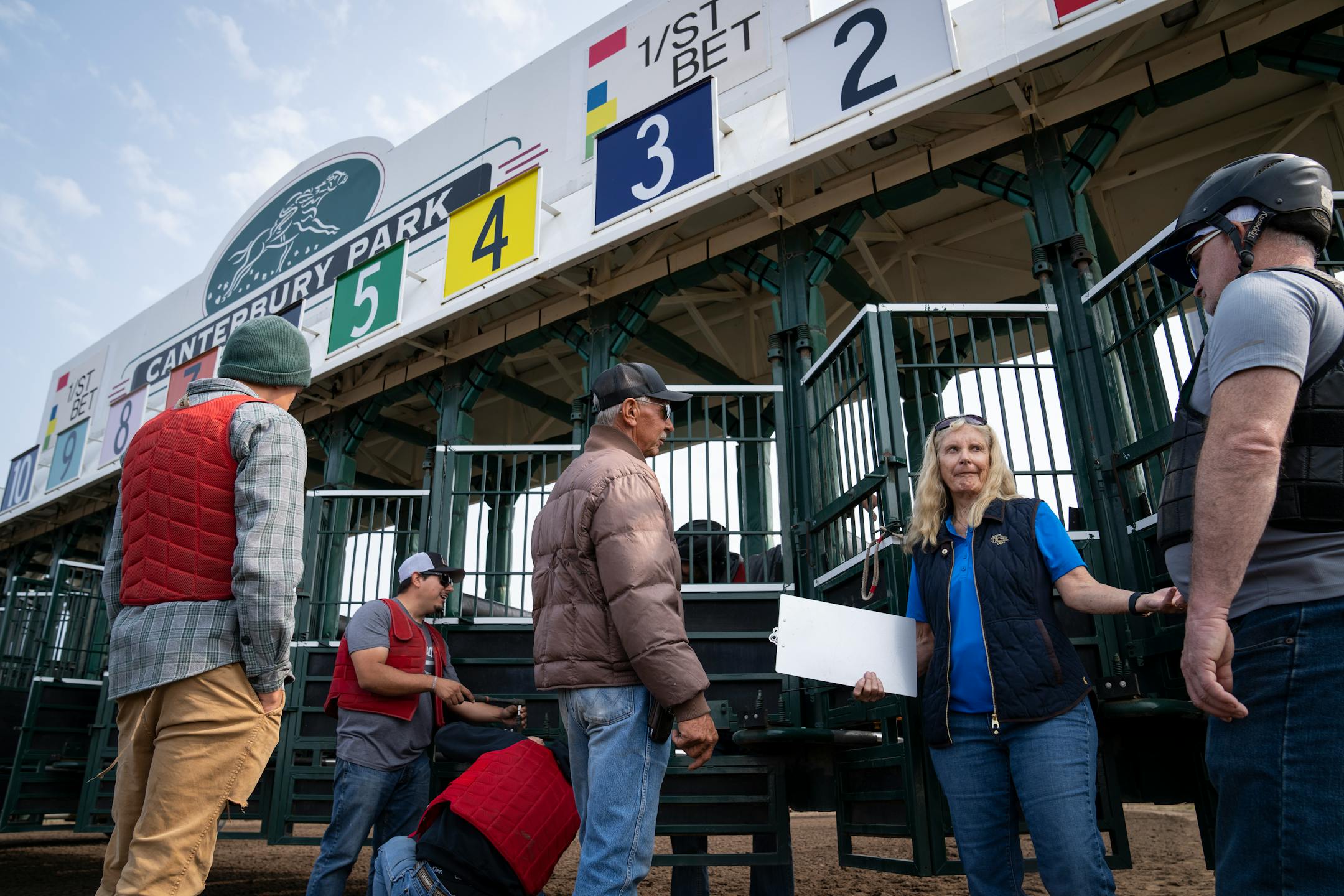 Dr. Lynn Hovda, second from right, talks to the starting crew, including starter Darrin Hall, center, and assistant starter Tim Neal, right, at Canterbury Park in Shakopee, Minn.