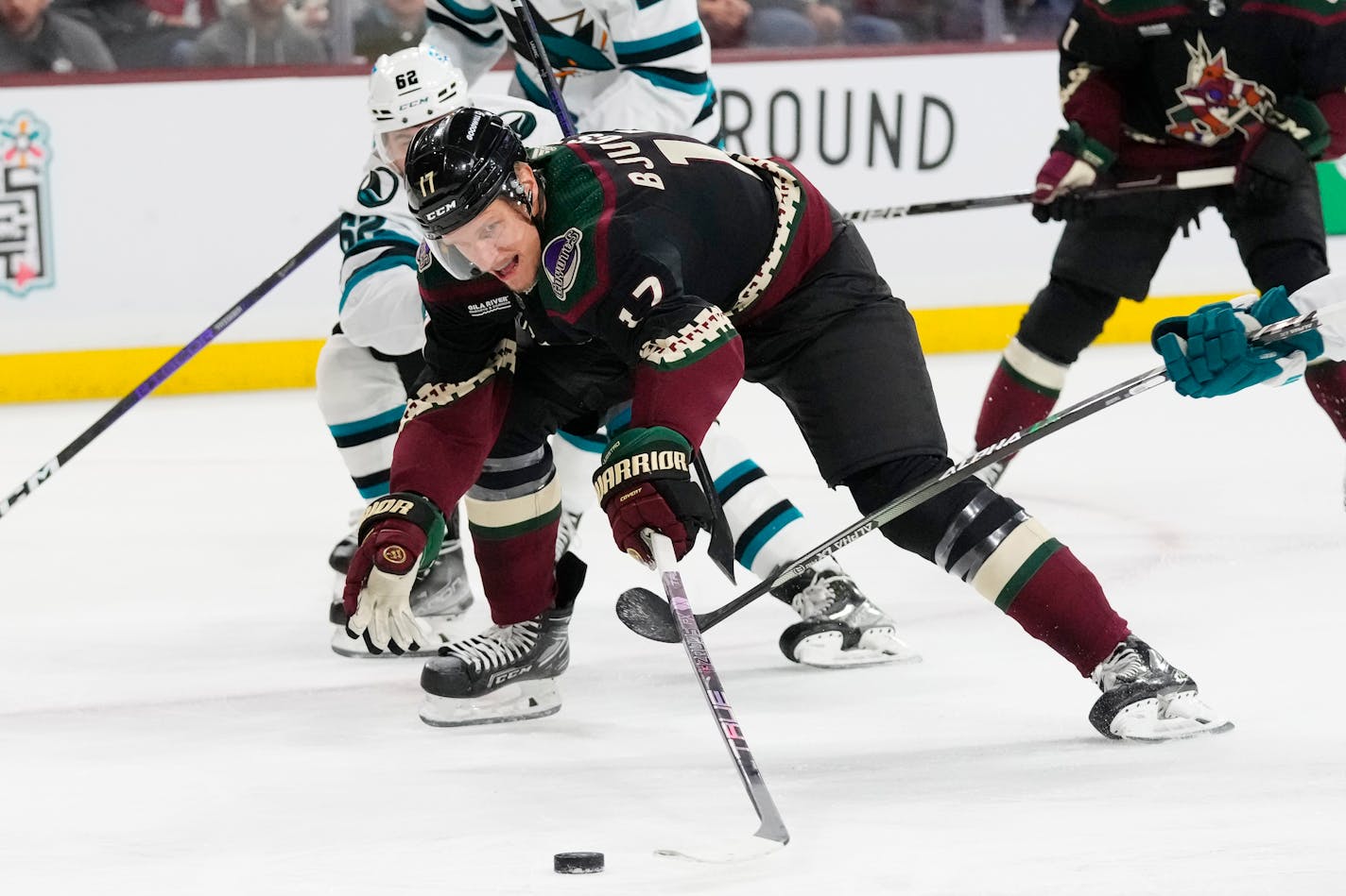 Arizona Coyotes center Nick Bjugstad (17) gets hooked by San Jose Sharks right wing Kevin Labanc (62) during the first period of an NHL hockey game in Tempe, Ariz., Tuesday, Jan. 10, 2023. (AP Photo/Ross D. Franklin)