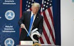 President Donald Trump shows the size of environmental impact road planning documents for a highway in Maryland while speaking about infrastructure pl