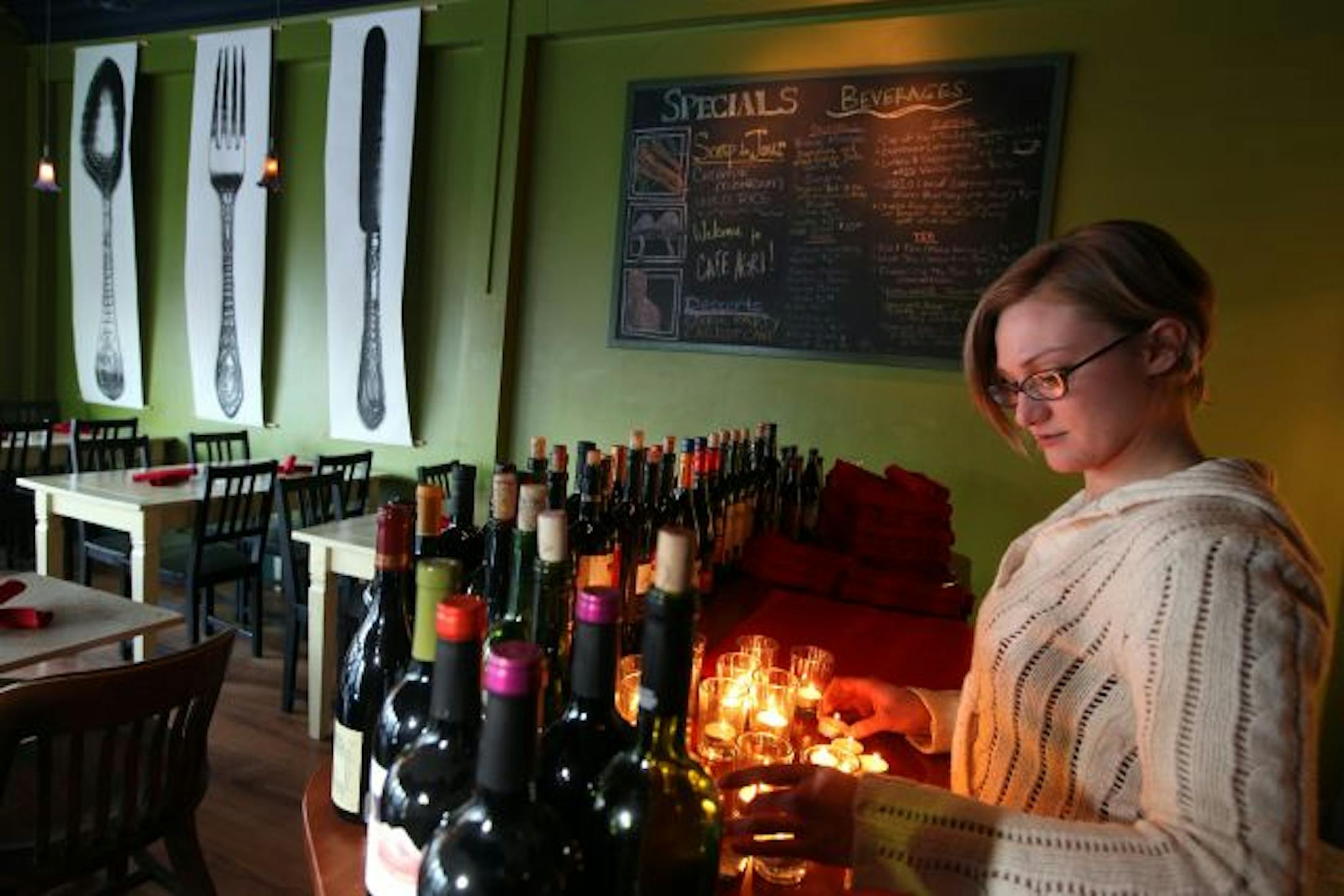 Server Laura Nelson preps for dinner service at a counter lined by the restaurant's selection of 23 red wines sold by the glass.