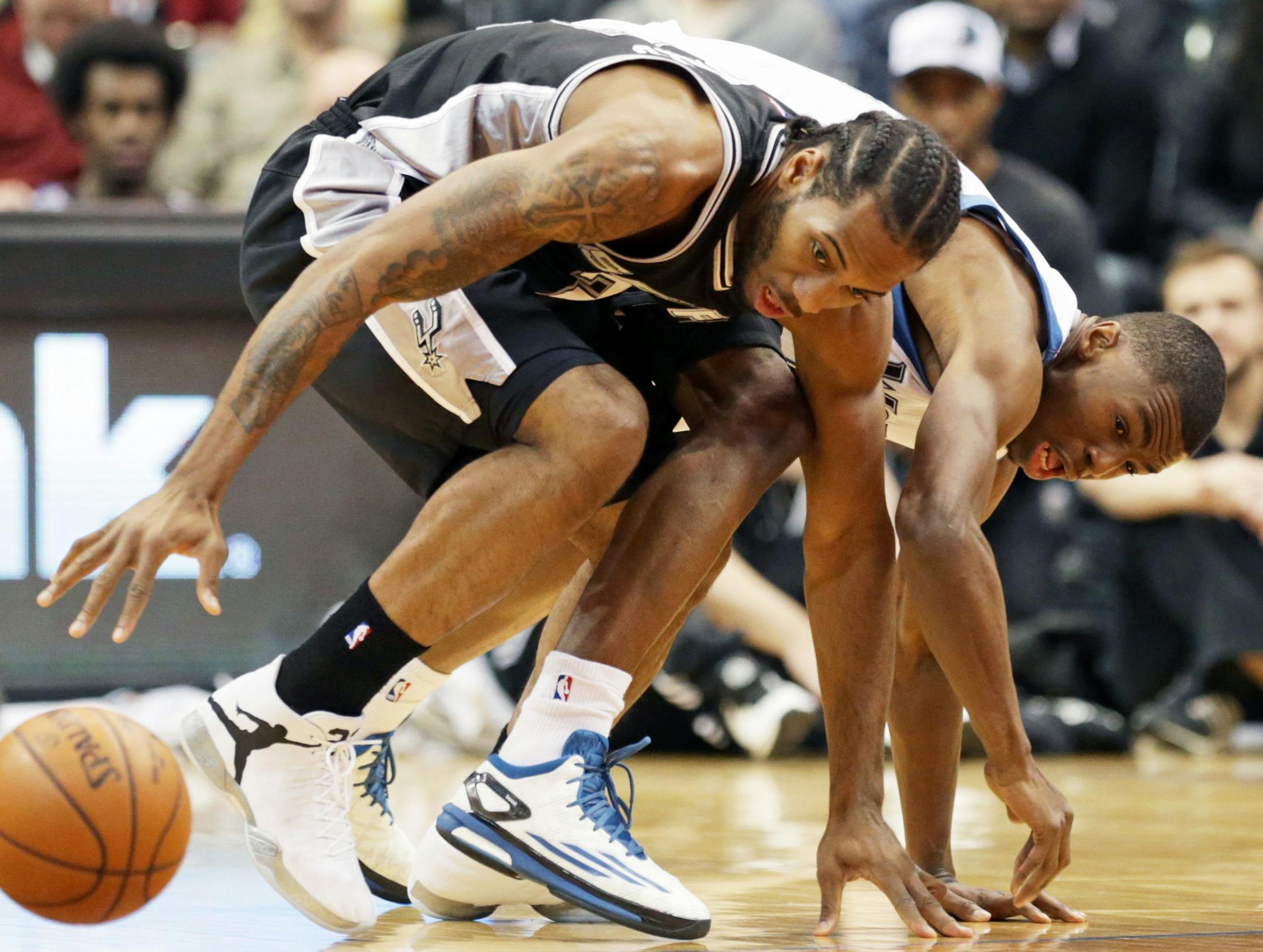 San Antonio Spurs’ Kawhi Leonard, left, and Minnesota Timberwolves’ Andrew Wiggins scramble for the loose ball in the first quarter of an NBA basketball game, Friday, Nov. 21, 2014, in Minneapolis. (AP Photo/Jim Mone)