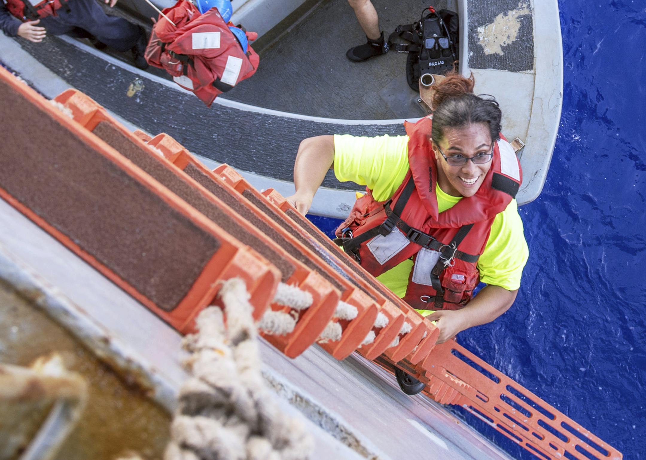 In this Wednesday, Oct. 25, 2017 photo, Tasha Fuiaba, an American mariner who had been sailing for five months on a damaged sailboat, climbs the accommodation ladder to board the amphibious dock landing ship USS Ashland after the Navy ship rescued two Honolulu women and their dogs after being lost at sea for several months while trying to sail from Hawaii to Tahiti. The U.S. Navy rescued the women on Wednesday after a Taiwanese fishing vessel spotted them about 900 miles southeast of Japan on Tu