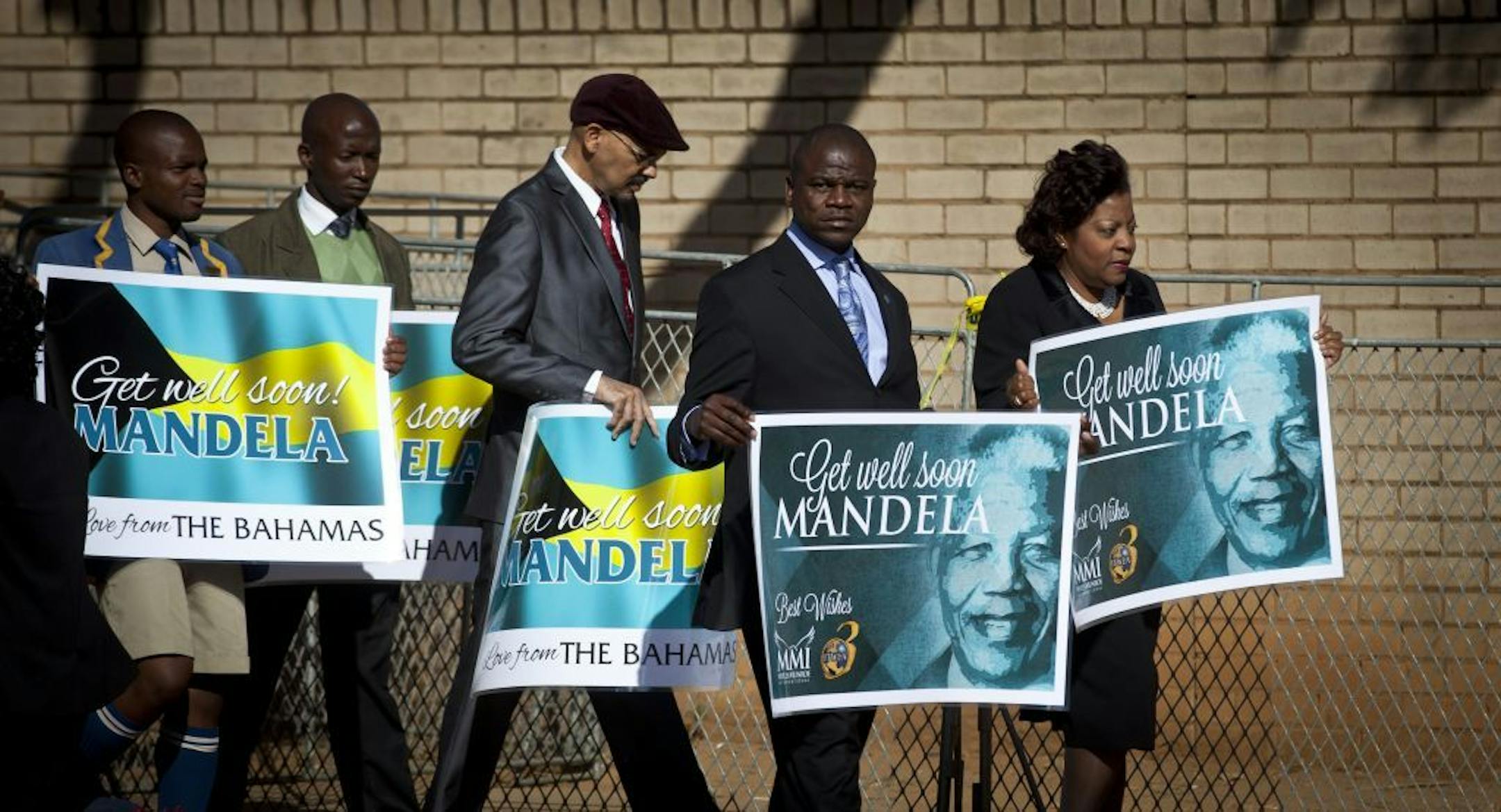 A group of wellwishers carrying get-well placards arrive at the Mediclinic Heart Hospital where former South African President Nelson Mandela is being treated in Pretoria, South Africa Sunday, June 16, 2013.