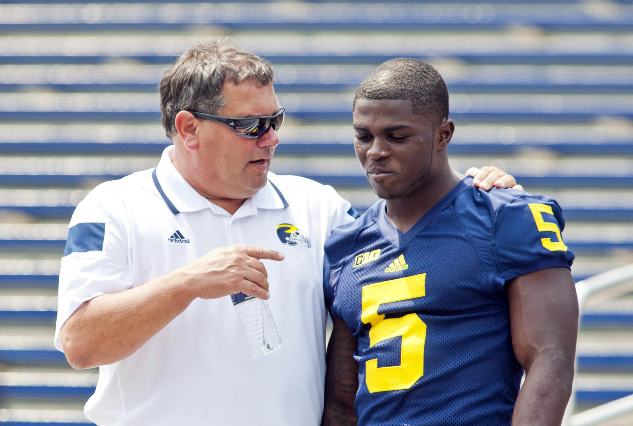Michigan head coach Brady Hoke, left, speaks with freshman cornerback Jabrill Peppers (5) after a team photo during the NCAA college football team's preseason media day, Sunday, Aug. 10, 2014, at Michigan Stadium in Ann Arbor, Mich. (AP Photo/Tony Ding)
