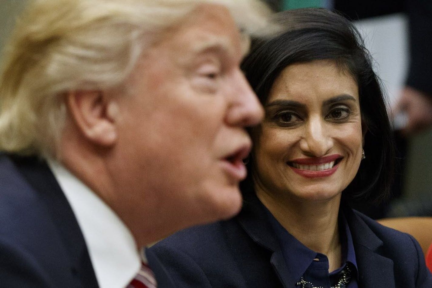 FILE - In this March 22, 2017 file photo, Administrator of the Centers for Medicare and Medicaid Services Seema Verma listen at right as President Donald Trump speaks during a meeting in the Roosevelt Room of the White House in Washington. The Trump administration says it's offering a path for states that want to seek work requirements for Medicaid recipients, and that's a major policy shift toward low-income people.