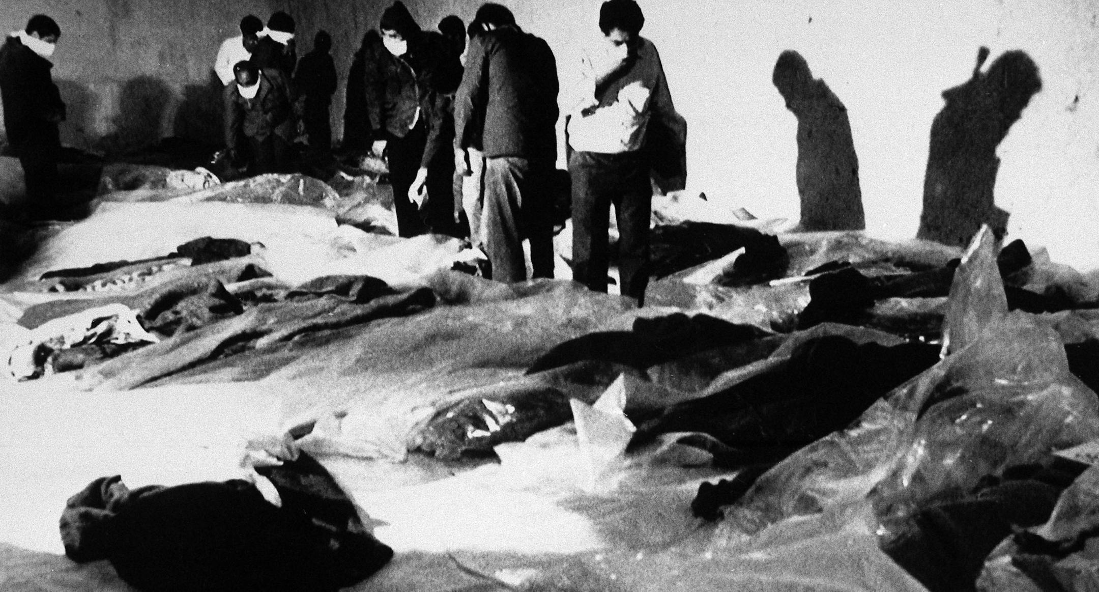 FILE - In this July 4, 1988 file photo, people looking for family members walk amid bodies of victims from Iran Air Flight 655 in a morgue in Bandar Abbas, Iran, a day after the plane was shot down over the Persian Gulf by the guided missile cruiser USS Vincennes while the plane was still in Iranian airspace. (AP Photo/The Canadian Press, Mohammad Sayyad)