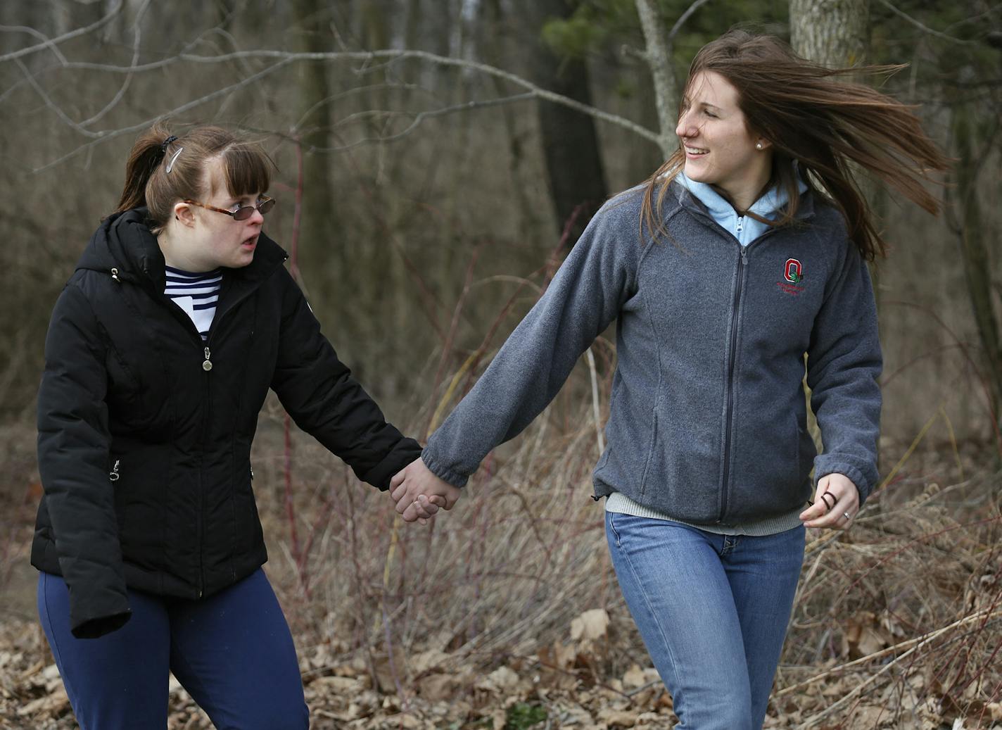 In this April 6, 2013 photo, Michelle Long, 23, right, of Grove City holds her sister Julia Truby, 17, hand of Worthington as they walk to the swing at Camp Willson in Bellefontaine, Ohio. They were participating in Ohio SIBS, an organization for adult siblings of people with developmental disabilities and their families. (AP Photo/The Columbus Dispatch, Eric Albrecht) ORG XMIT: MIN2013052115155836