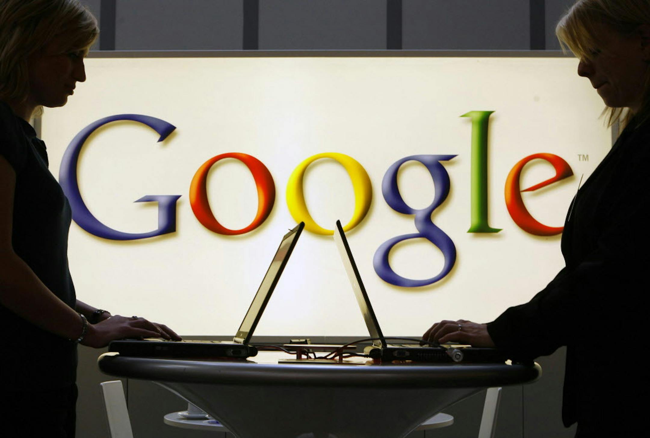 FILE- In this April 17, 2007 file photo, exhibitors of the Google company work on laptop computers in front of an illuminated sign of the Google logo at the industrial fair Hannover Messe in Hanover, Germany. Google&#xed;s removal of search results in Europe is drawing accusations of press censorship, as stories from some of the continent&#xed;s most prominent news outlets begin vanishing. The U.S. Internet giant said Thursday it is getting 1,000 requests a day to scrub results. The U.S. firm mu