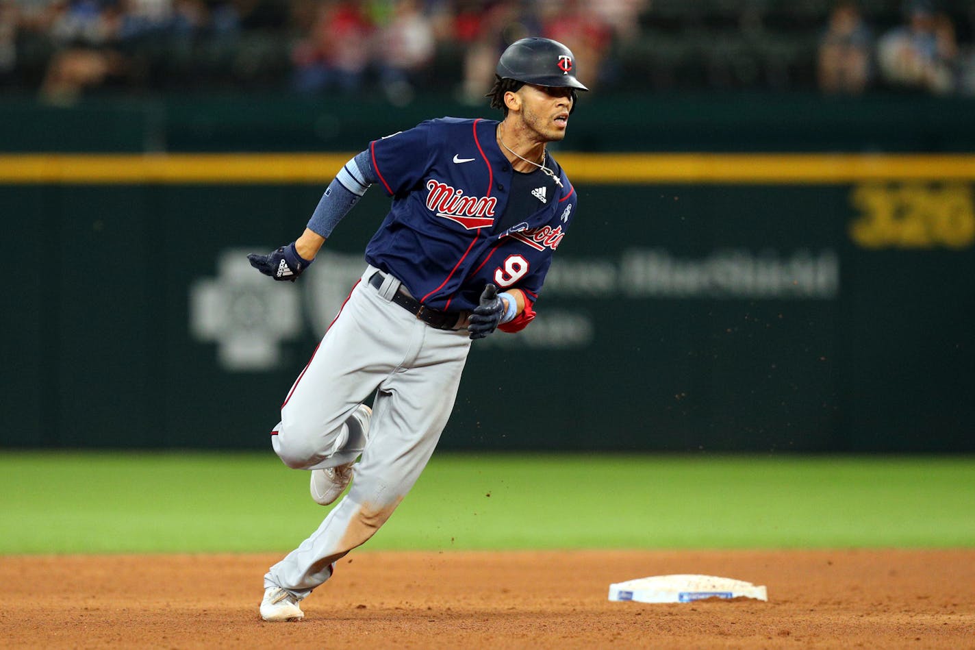 Minnesota Twins Andrelton Simmons (9) runs to third on a throwing error in the eighth inning against the Texas Rangers at a baseball game Sunday, June 20, 2021, in Arlington, Texas. (AP Photo/Richard W. Rodriguez)