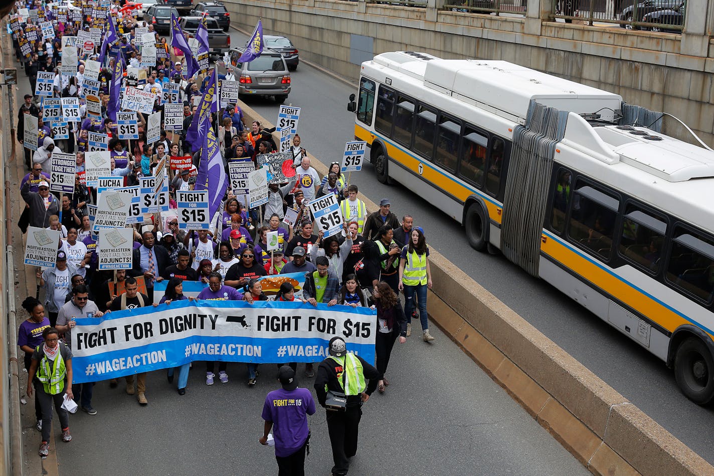 Thirty-year-old David Coulombe (behind banner), who works as a consumables sales floor associate at Walmart, participates in a march and rally for $15 minimum wage in Boston, Massachusetts April 14, 2015. REUTERS/Brian Snyder