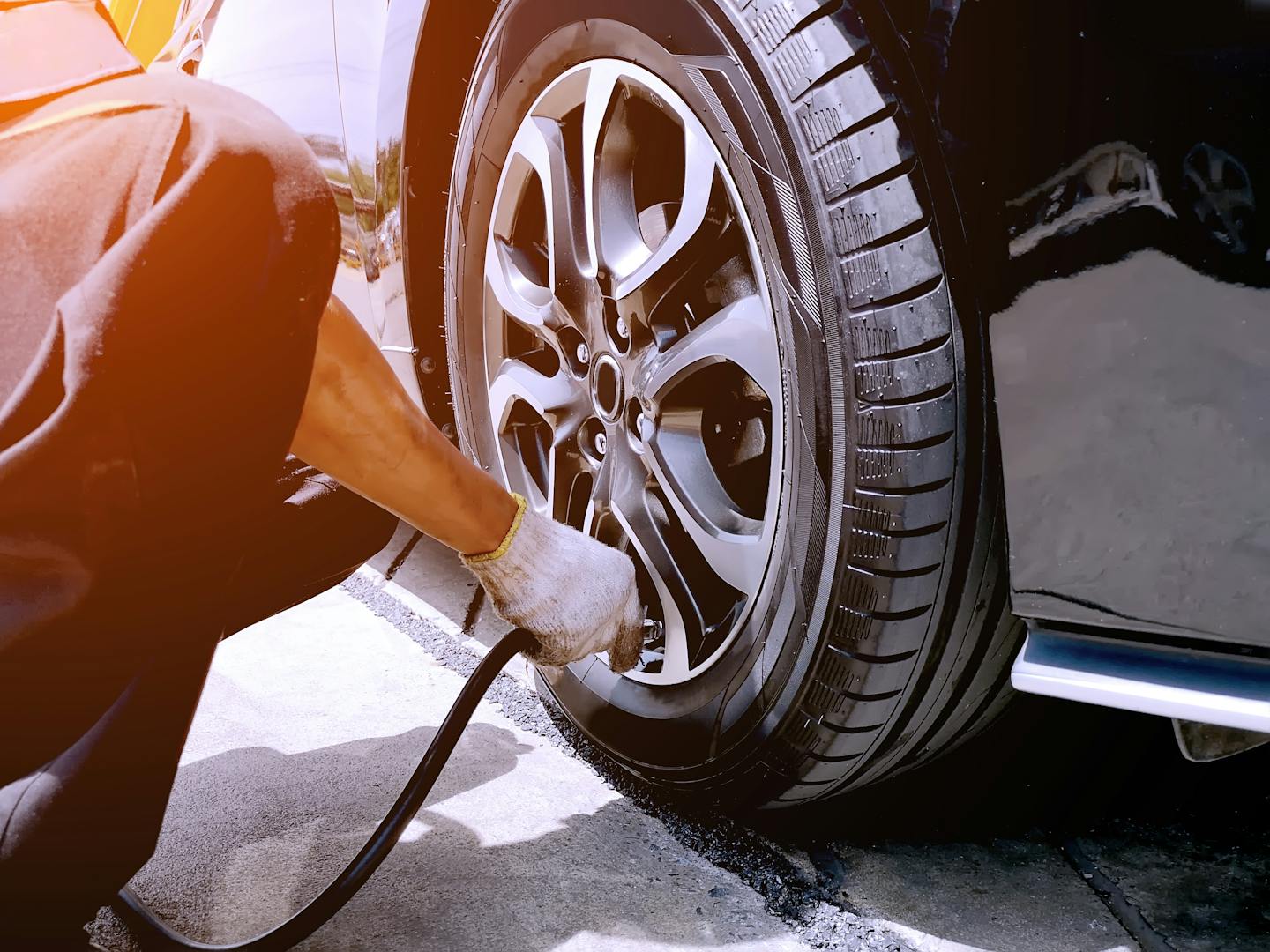 The mechanic is filling the car tires at the garage. The technician is checking the tire condition to prevent accidents.