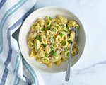 A bowl of orecchiette pasta with peas, pancetta and fresh herbs.